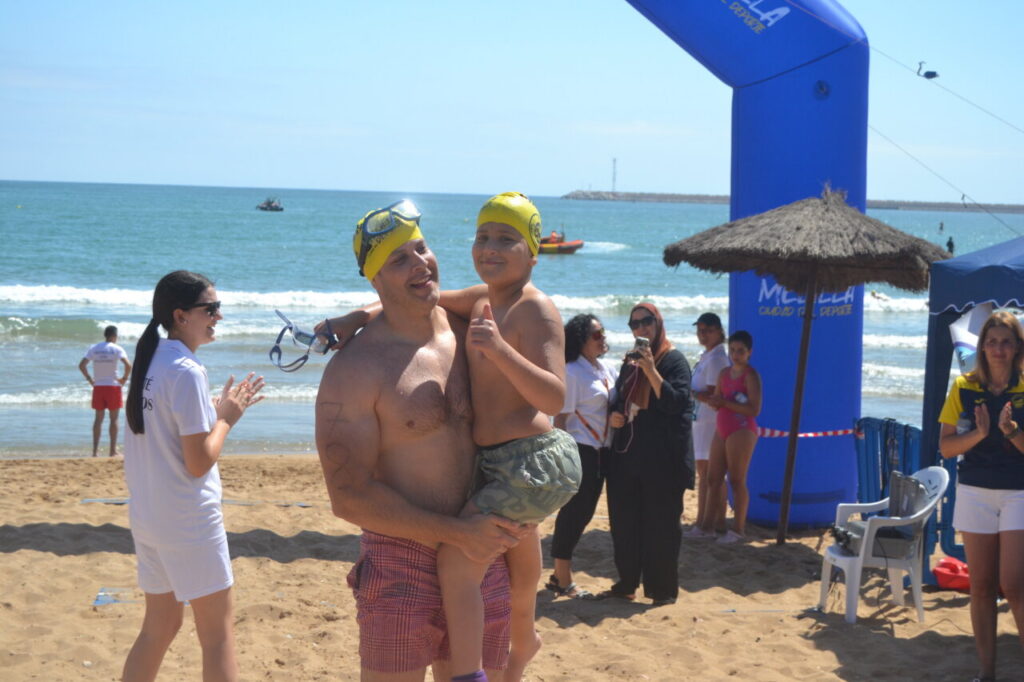 Padre e hijo celebrando en la playa tras la travesía a nado.