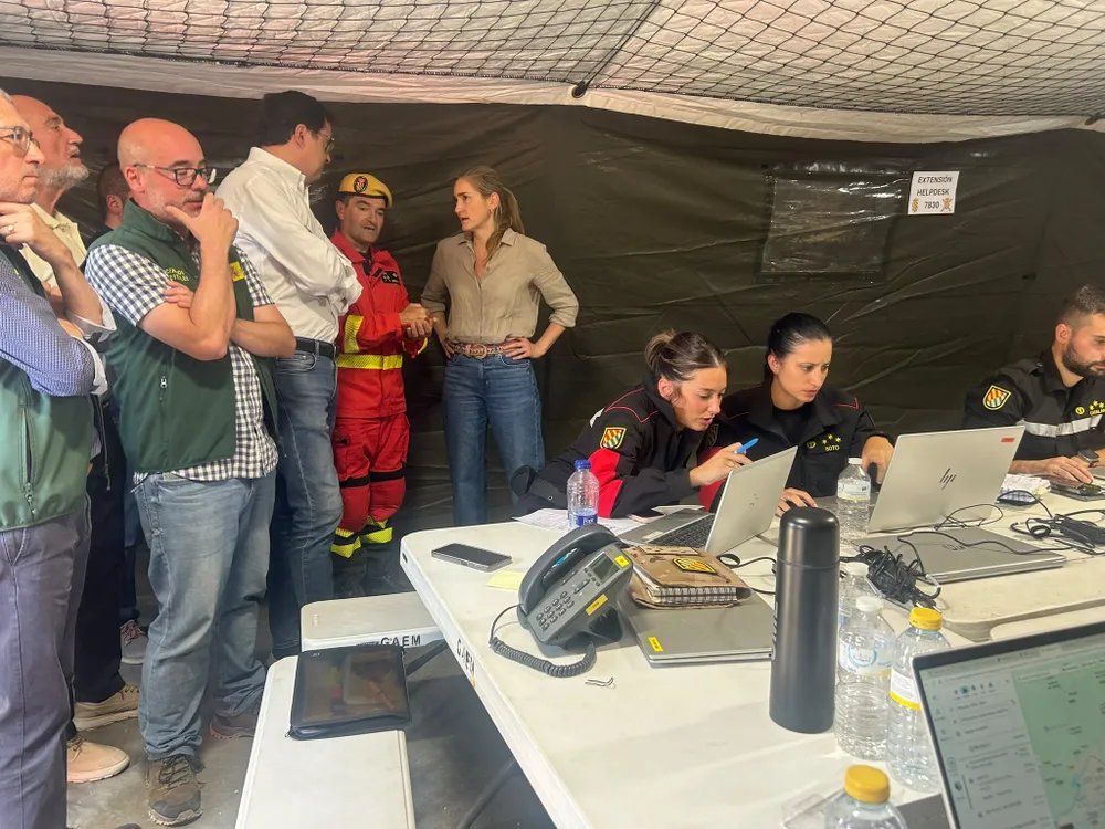 Incendios forestales en Madrid 2023 - MelillaHoy Emergency responders and officials gather at a table with laptops inside a tent for an emergency briefing or coordination session.