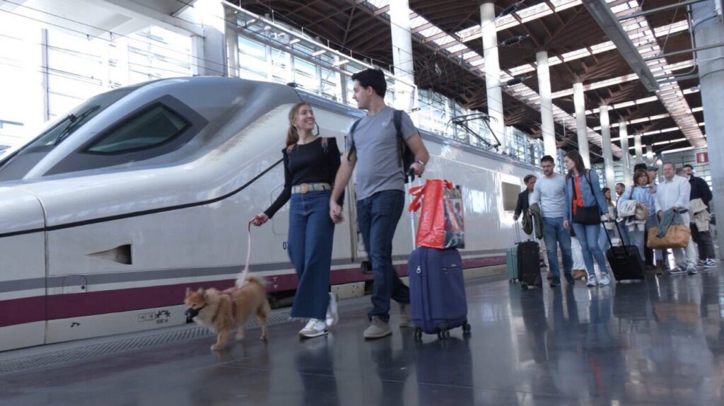 Pareja caminando con perro en estación de tren Renfe