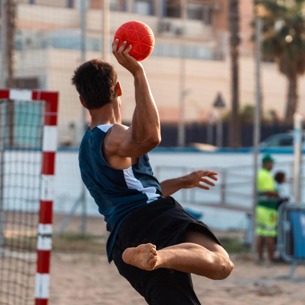 Jugador lanzando un balón de balonmano playa en un torneo