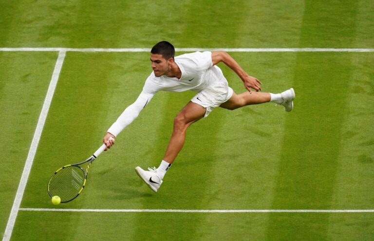 Carlos Alcaraz jugando tenis en una cancha de césped