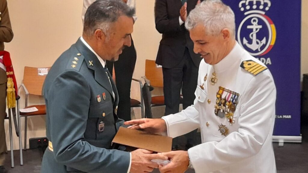 Dos oficiales militares intercambiando un objeto durante un acto ceremonial en Melilla.
