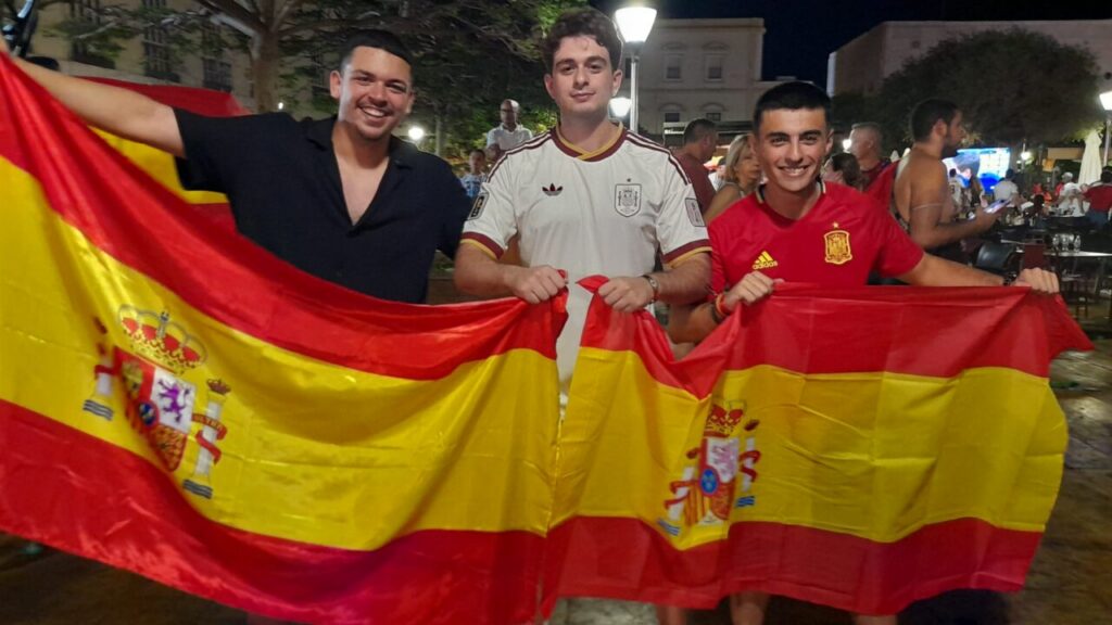 Tres jóvenes sosteniendo banderas de España en una celebración