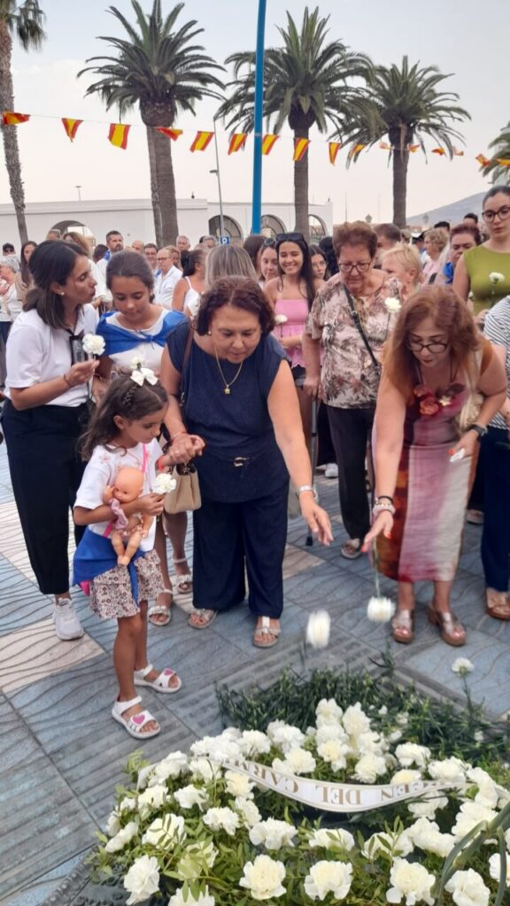 Personas depositando flores en la ofrenda a la Virgen del Carmen
