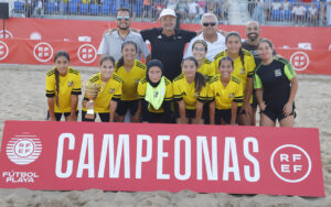 Equipo femenino infantil del Gimnástico Melilla con trofeo en la playa