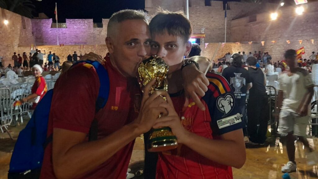 Dos aficionados celebrando con el trofeo de la Copa del Mundo en Melilla