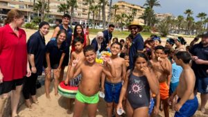 Grupo de niños y monitores en la playa durante el campamento de inglés.