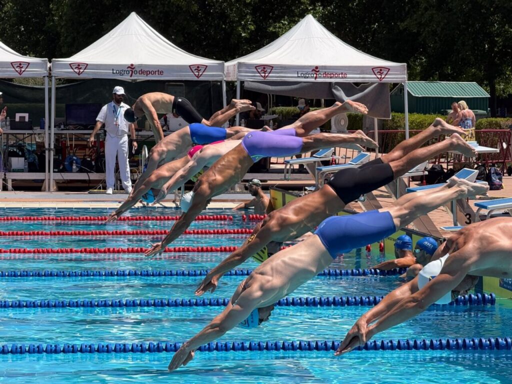 Nadadores saltando al agua en un campeonato de natación
