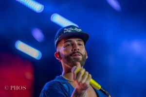 Manuel Turizo en concierto con micrófono amarillo y fondo iluminado