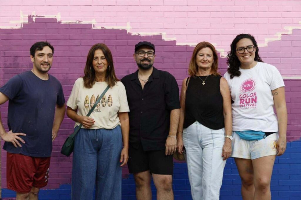 Grupo de personas posando frente a un mural colorido en Melilla