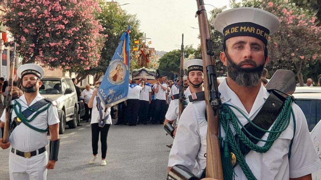Procesión marinera en Melilla con la Virgen del Carmen y participantes en uniforme.