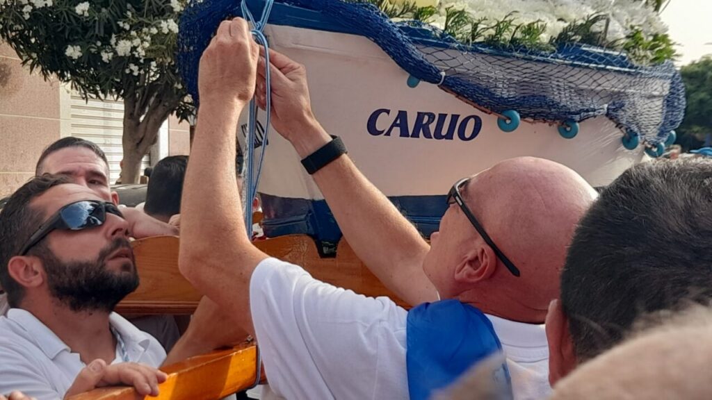 Hombres preparando la embarcación para la procesión marinera en Melilla.