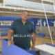 Man in a teal polo leaning on a blue railing inside an indoor basketball gym; blue walls and bleachers behind him, with the text 'MELILLA HOY' overlaid.