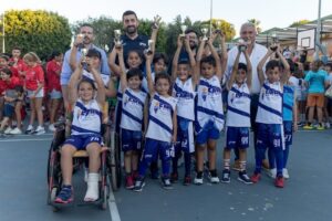 Niños y niñas celebrando con trofeos en un evento de baloncesto
