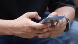 Persona usando un teléfono móvil para buscar información sobre estafas digitales