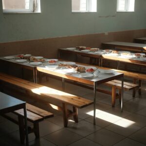 Comedor escolar vacío con platos y comida preparada en mesas