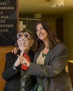 Fernando Arrabal y una mujer sonriente en ceremonia de reconocimiento cultural.