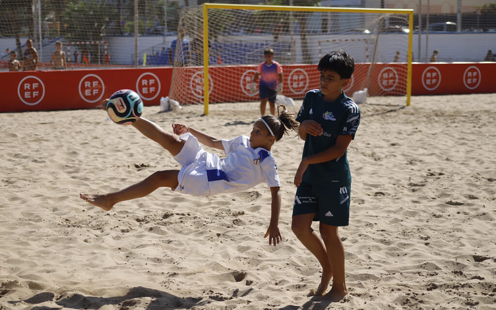 Niña realizando una acrobacia en un partido de fútbol playa