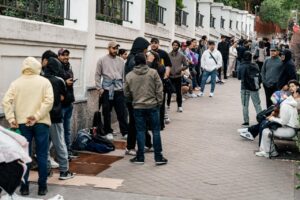 Grupo de personas esperando en la calle para regularización migratoria