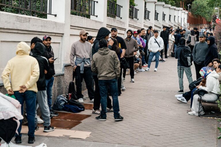 Grupo de personas esperando en la calle para regularización migratoria