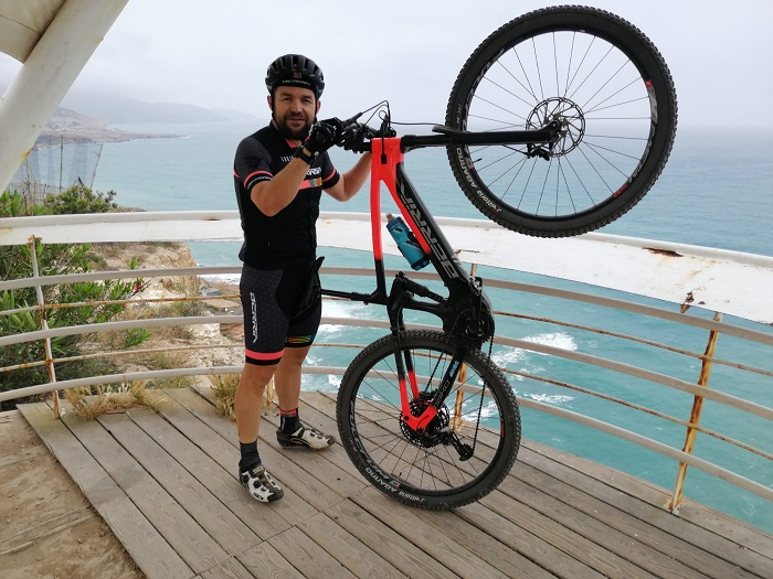 Javi Iglesias sosteniendo su bicicleta frente al mar en Melilla