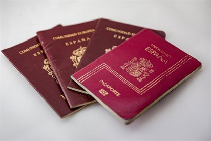 Several burgundy Spanish passports fanned together on a white surface.