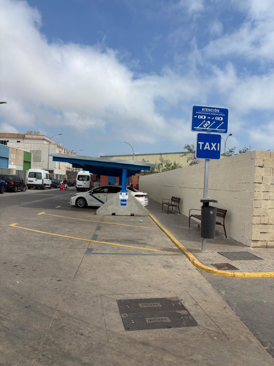 Marquesinas en el aparcamiento de taxis en la frontera con vehículos estacionados.