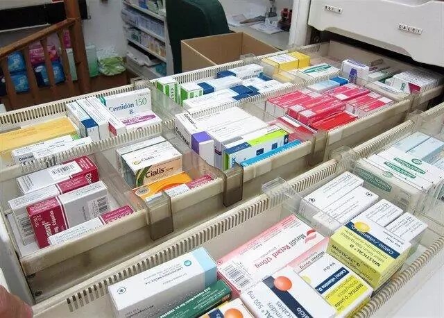 Diversos medicamentos organizados en estantes de farmacia