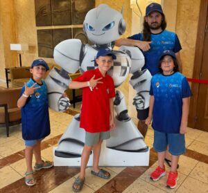 Niños y un adulto posando con un robot en un evento de ajedrez