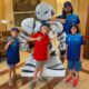 Niños y un adulto posando con un robot en un evento de ajedrez