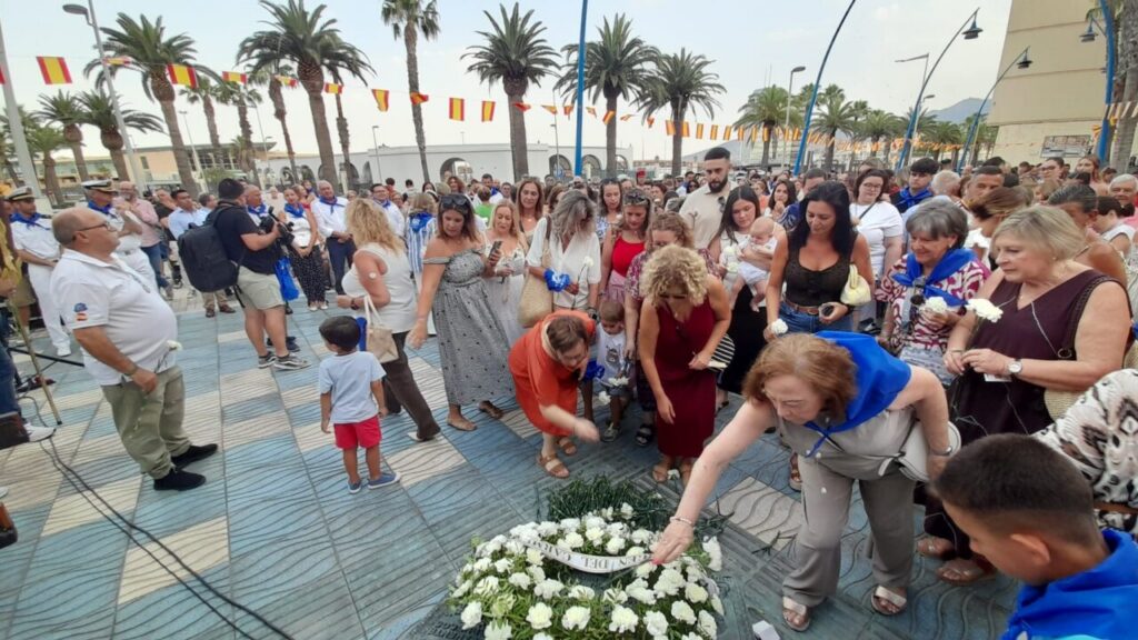 Personas depositando flores en la ofrenda a la Virgen del Carmen en Melilla