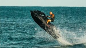 Hombre realizando acrobacias en moto acuática en el mar