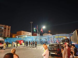 Vista nocturna de la frontera entre Melilla y Marruecos con personas y vehículos.