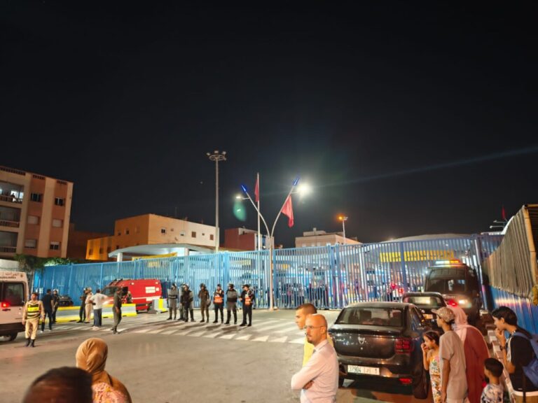 Vista nocturna de la frontera entre Melilla y Marruecos con personas y vehículos.