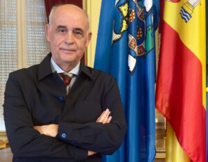 Retrato de un hombre con brazos cruzados frente a banderas