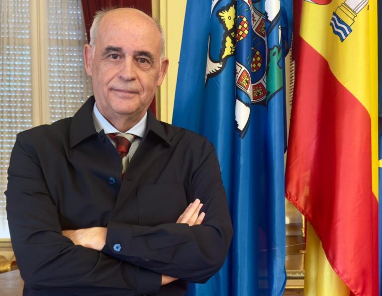 Retrato de un hombre con brazos cruzados frente a banderas