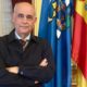Retrato de un hombre con brazos cruzados frente a banderas
