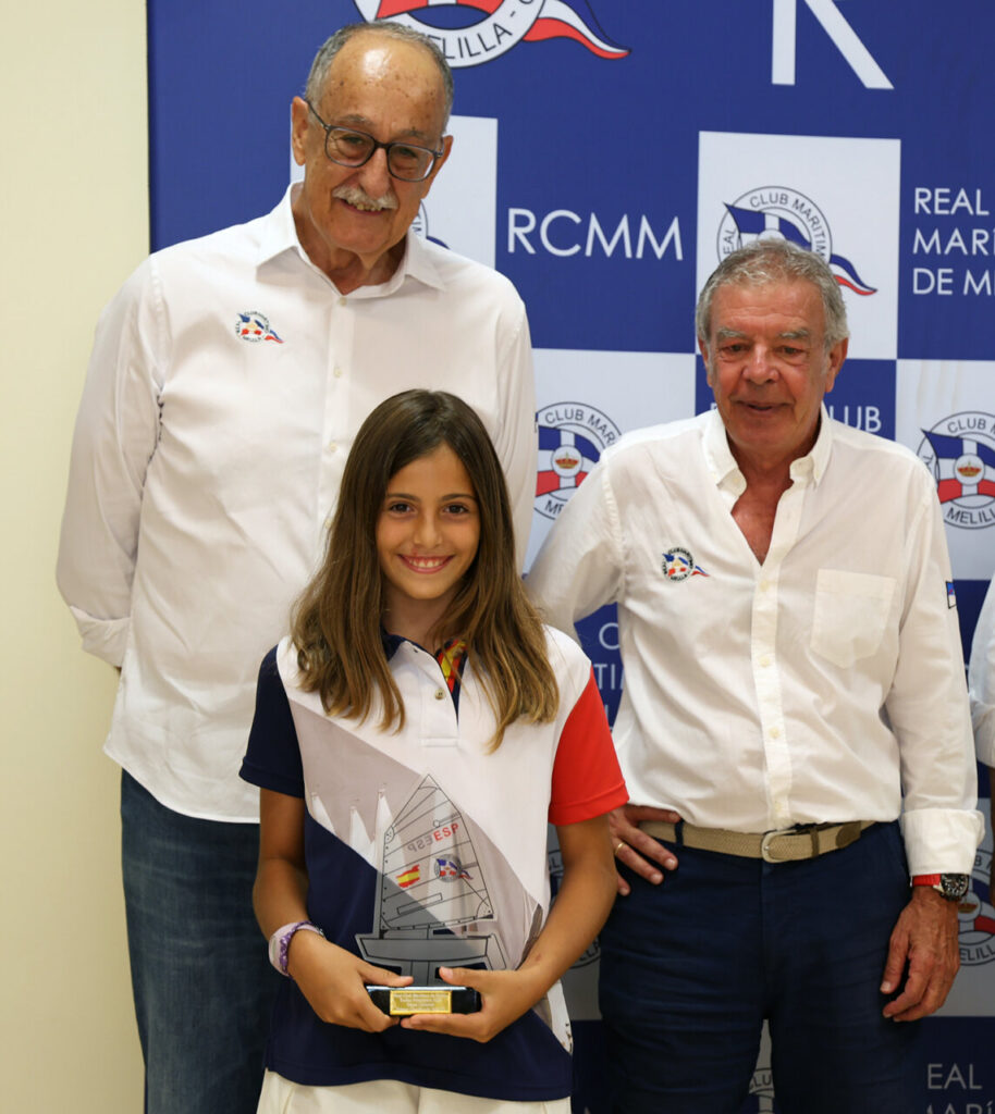Niña sonriente sosteniendo un trofeo en evento del Real Club Marítimo de Melilla