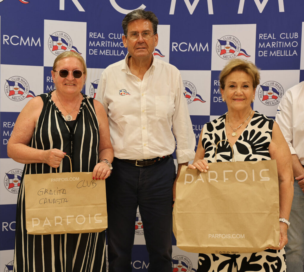 Three adults pose for a photo in front of a blue backdrop with RCMM logos; two women hold PARFOIS shopping bags while a man stands between them.