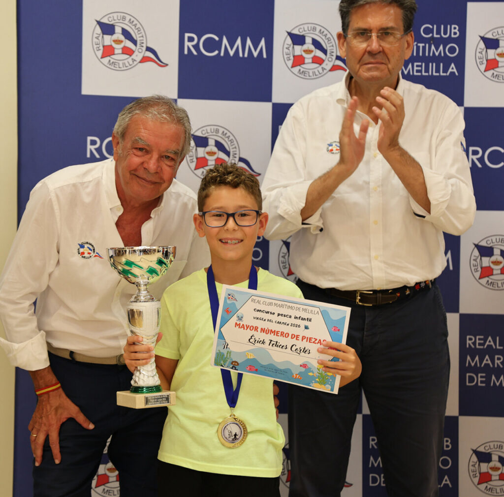 Niño sosteniendo trofeo y diploma en evento de pesca infantil