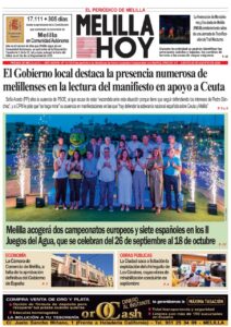 Group of officials posing on a stage with fireworks at a Melilla event, celebrating local achievements.