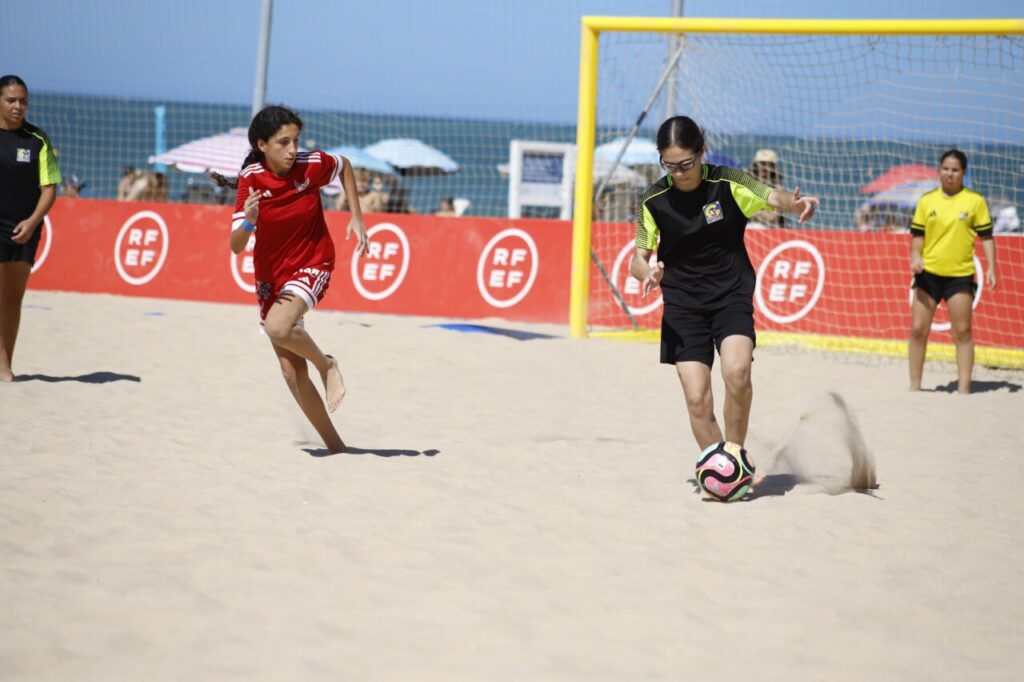 Jugadoras de fútbol playa compitiendo en la arena durante un partido