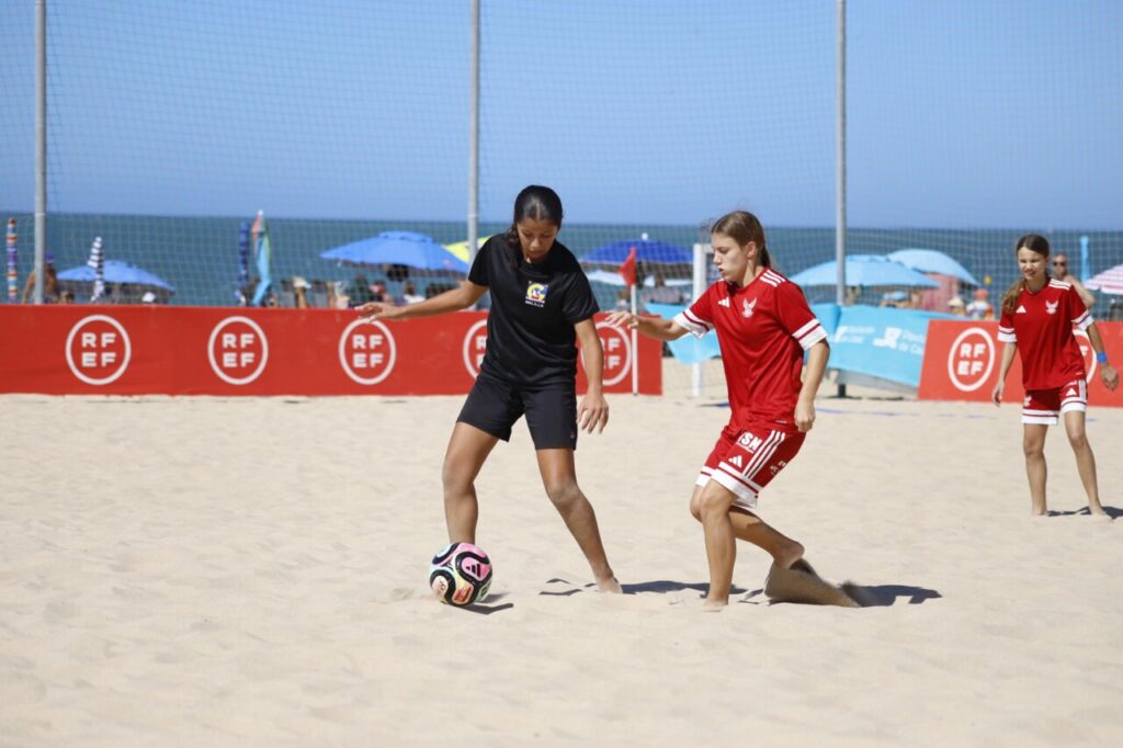 Jugadoras de fútbol playa en acción durante un partido en la playa.