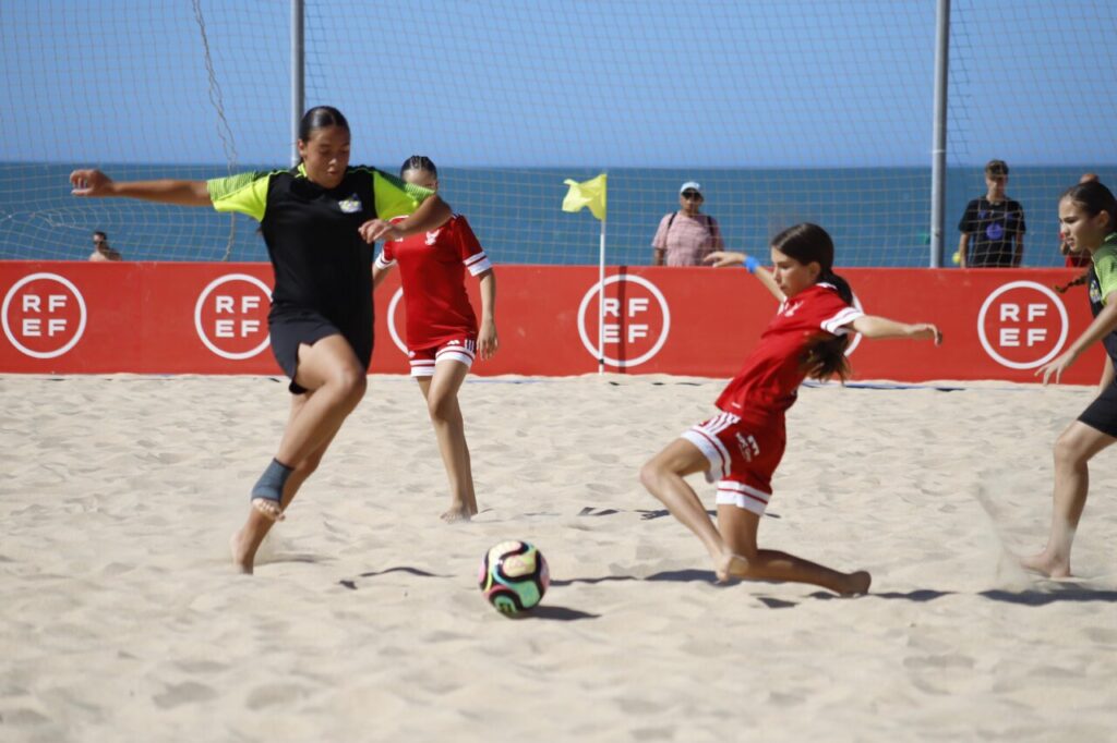 Jugadoras de fútbol playa compitiendo en la arena durante un partido