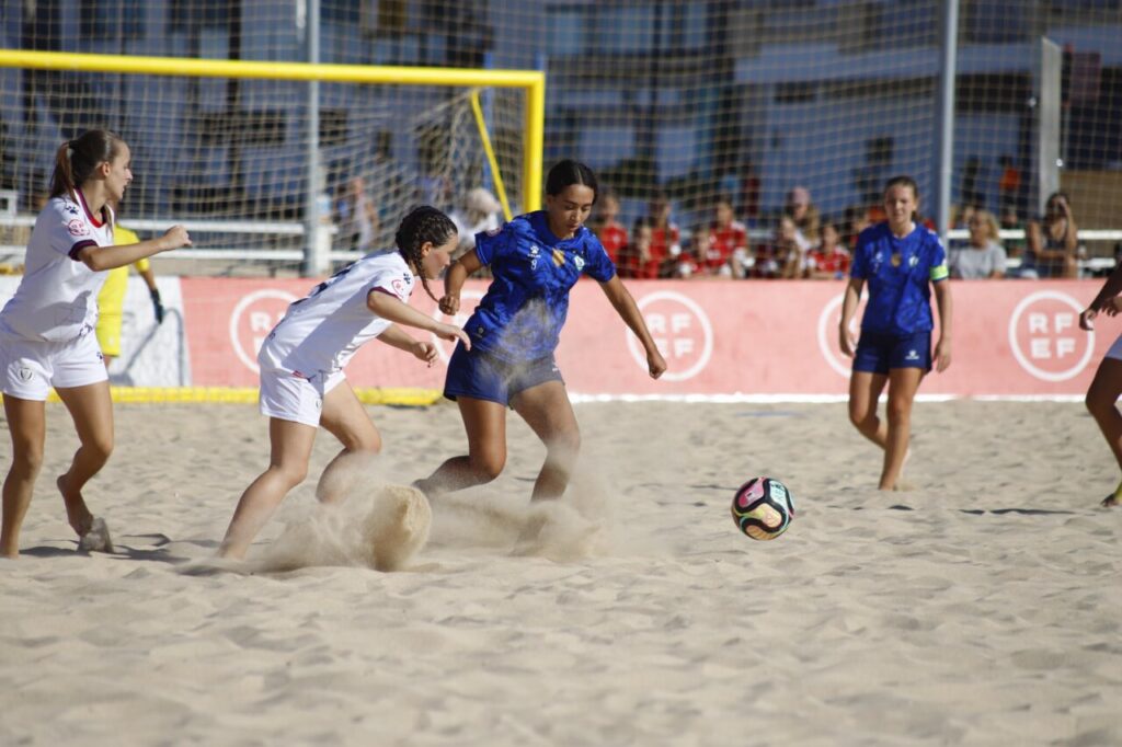 Jugadoras de fútbol playa compitiendo en la arena durante un partido