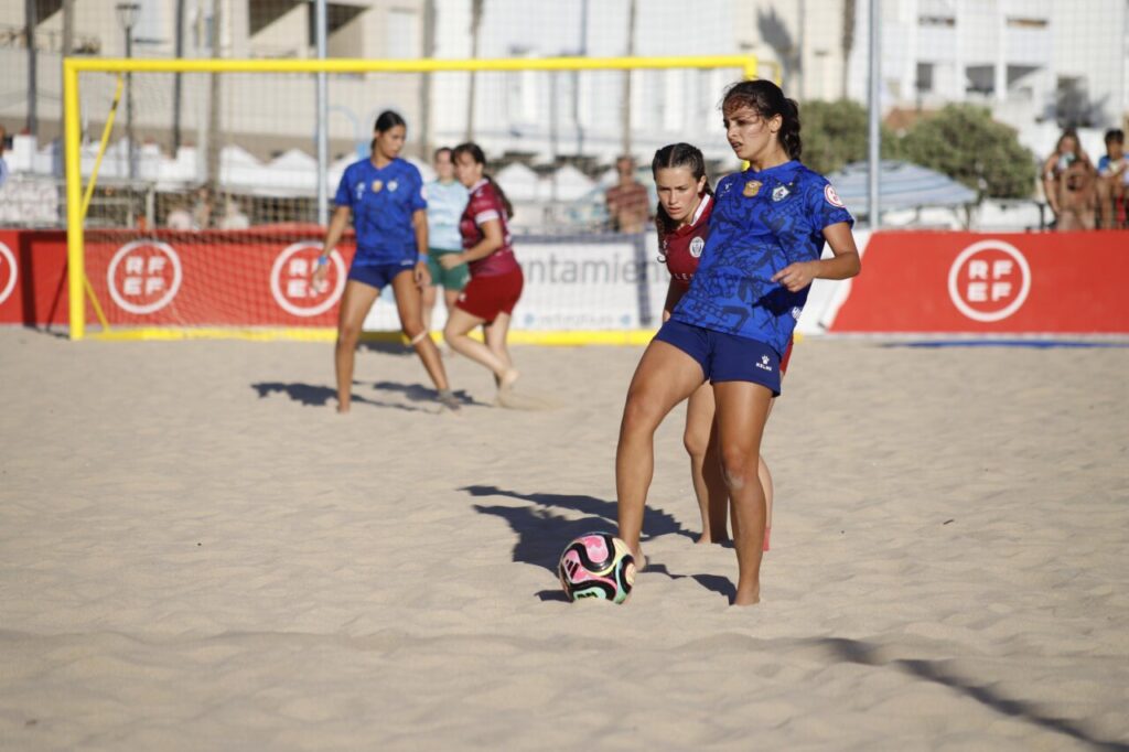 Jugadoras de fútbol playa en acción en la arena durante un partido