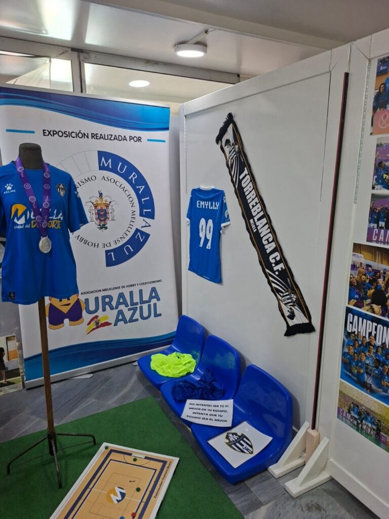 Exhibit booth featuring blue jerseys, a silver medal on a stand, and a large banner reading Muralla Azul.