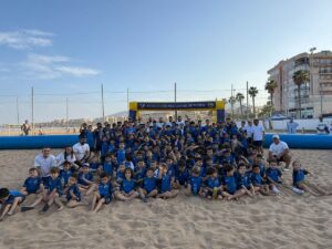 Grupo de niños en la playa participando en actividad de fútbol