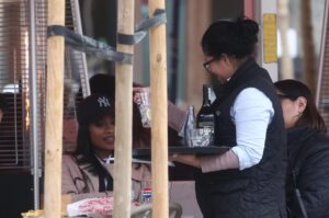 Mujer sirviendo bebidas en un restaurante con clientes extranjeros