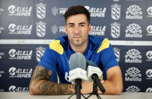 Alejandro en rueda de prensa con micrófonos y fondo del club Melilla